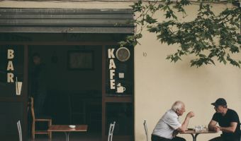 two men sitting outside of a cafe