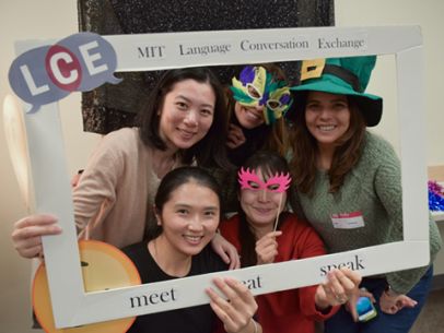 Five LCE members posing in for a photo wearing colorful masks and party hats